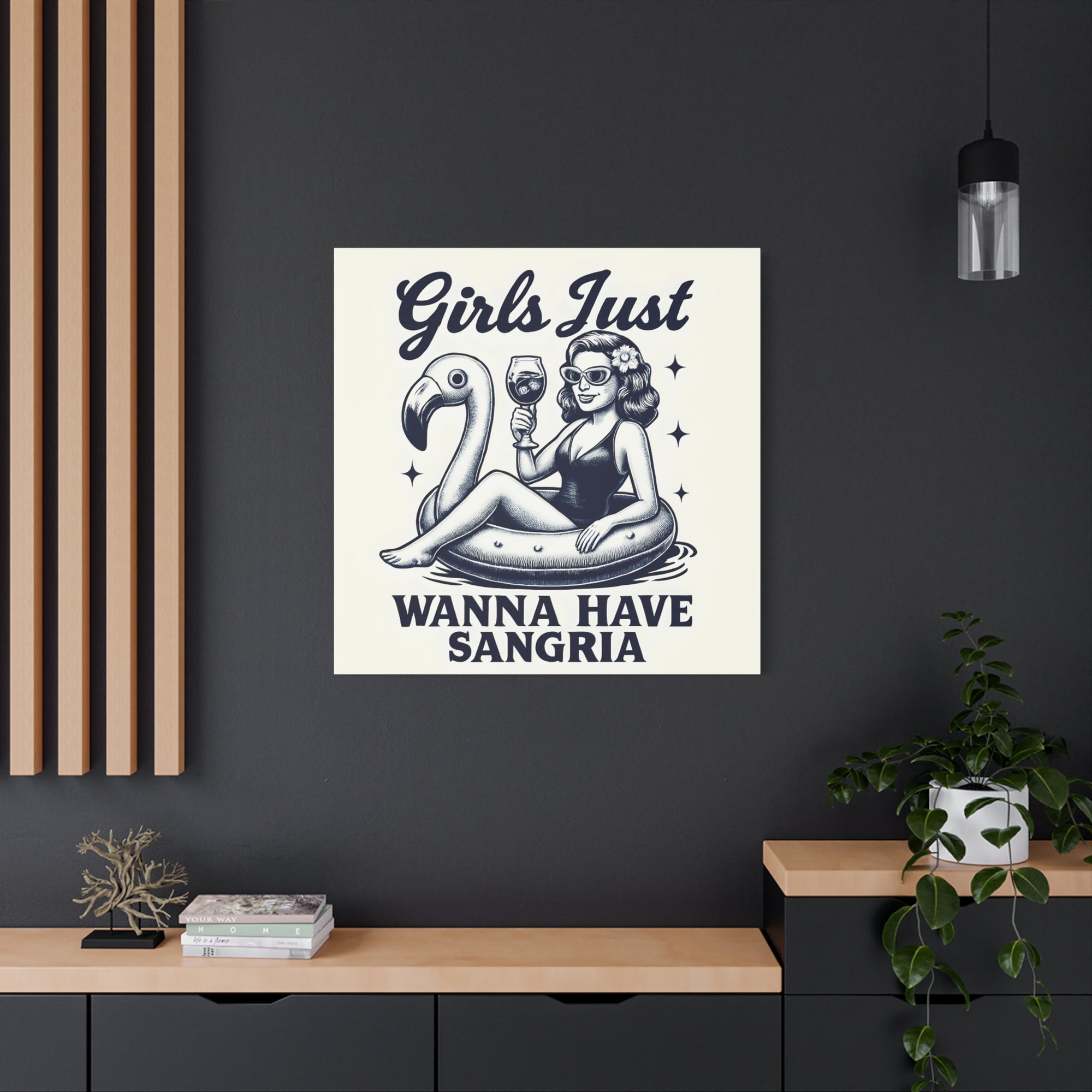 Poster with a design of a woman on an inner tube with a flamingo, text 'Girls Just Wanna Have Sangria', in a modern interior setting.