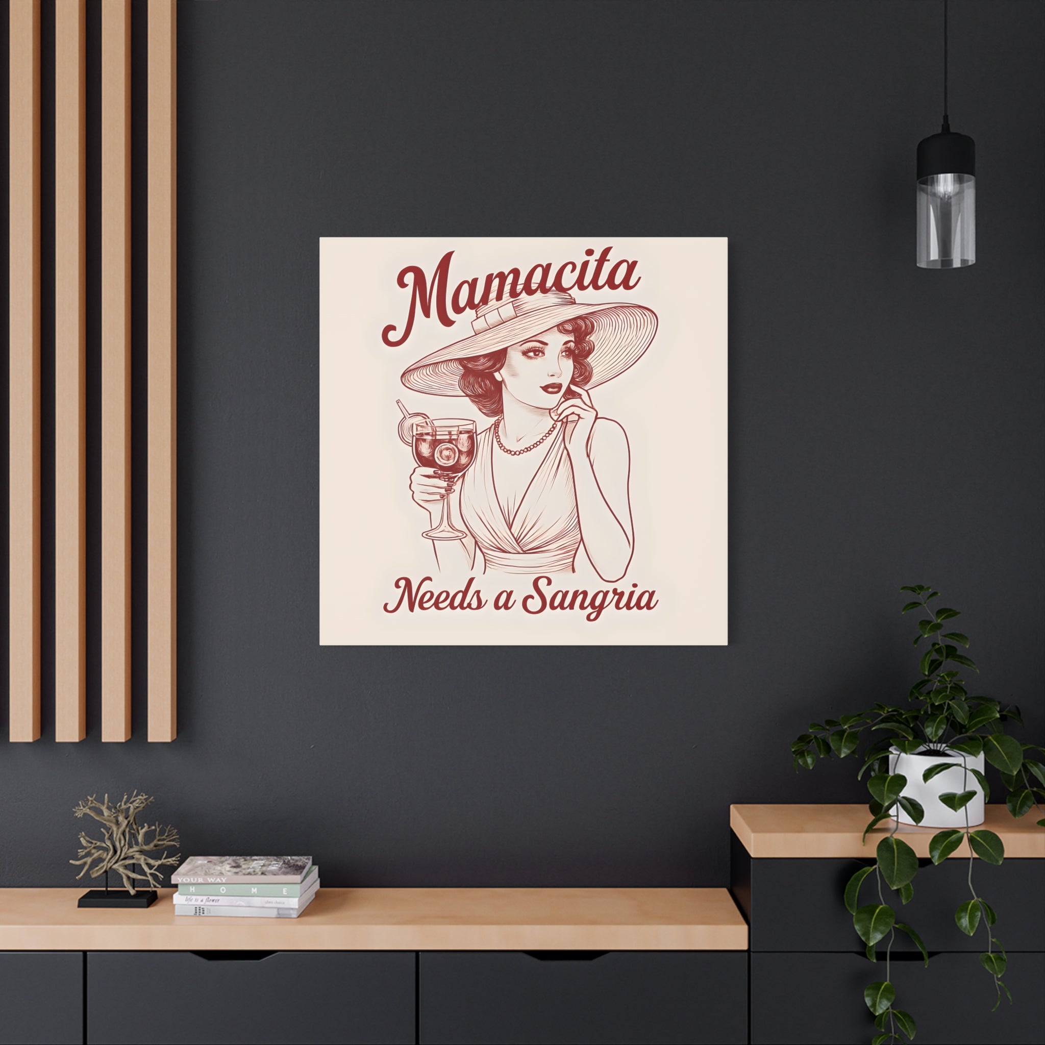Framed artwork of a woman with 'Mamacita Needs a Sangria' text on a dark wall.