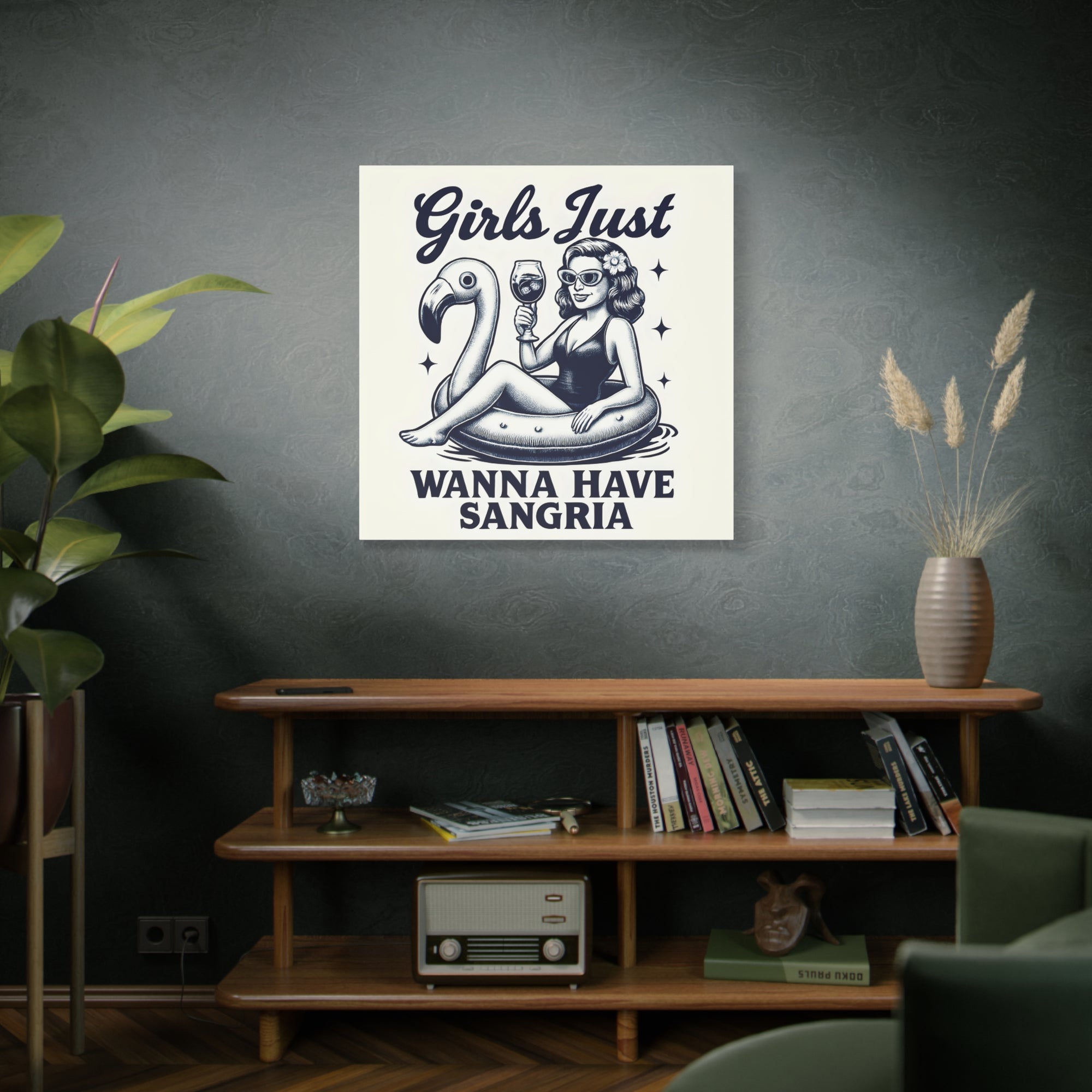 Poster with a design of a woman on an inner tube with a flamingo, text 'Girls Just Wanna Have Sangria', in a room with a shelf and decor.