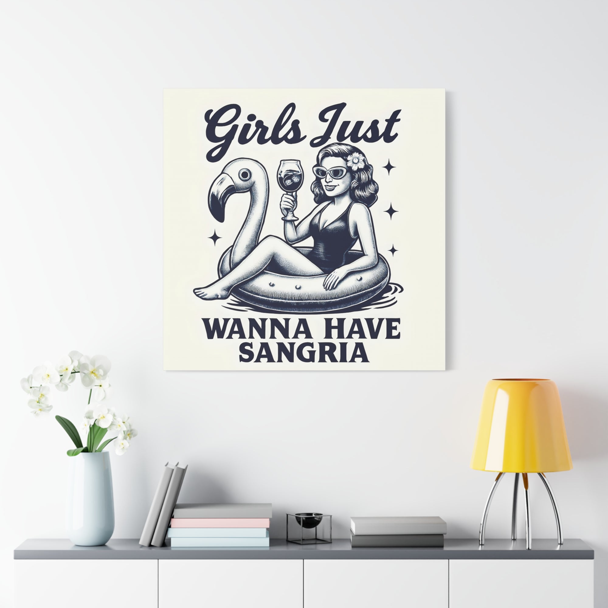 Canvas print with a design of a woman on an inflatable flamingo, holding a glass of wine, with text 'Girls Just Wanna Have Sangria' on a white wall above a shelf.