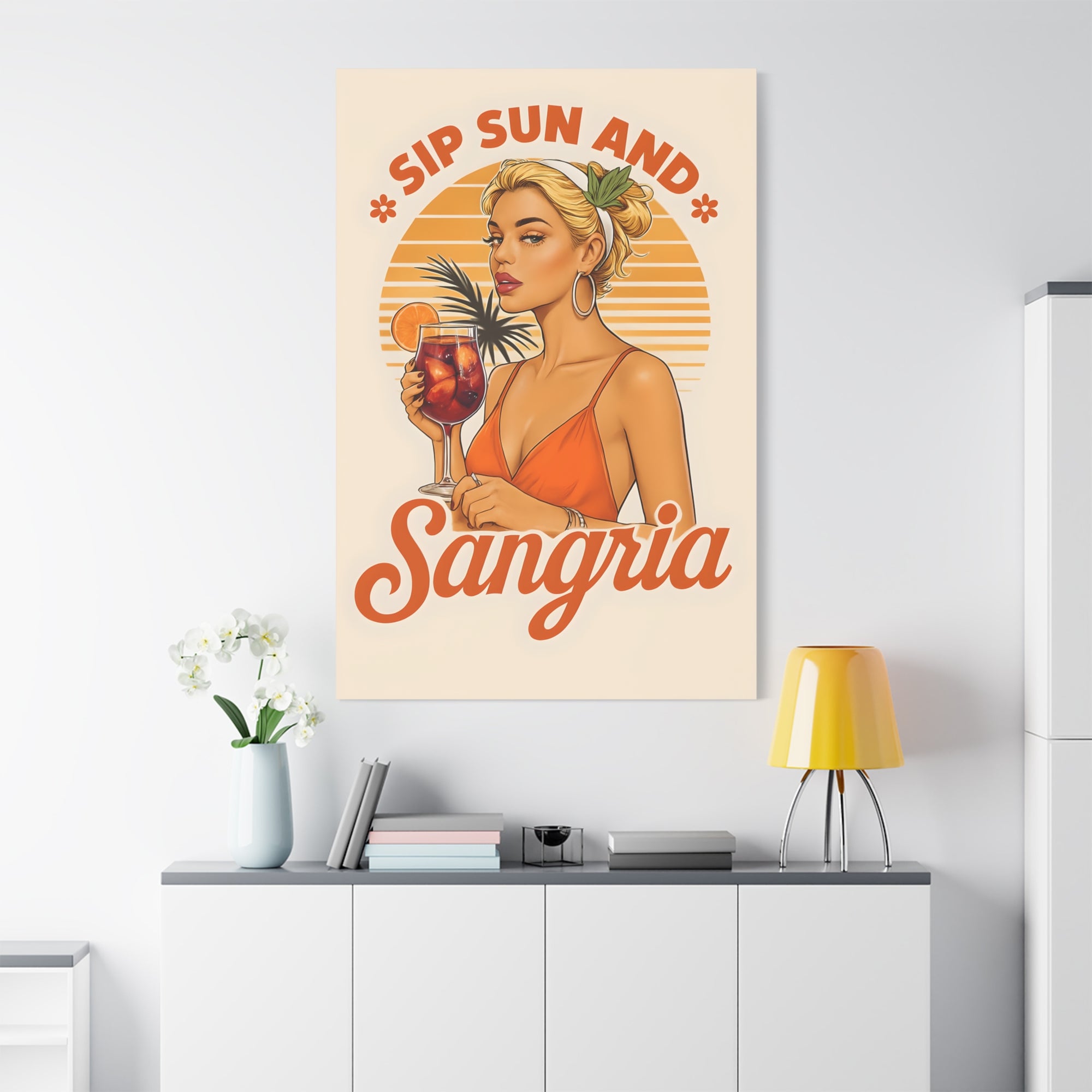 Poster with a woman holding a drink and the text 'Sip Sun And Sangria' on a wall above a white cabinet.